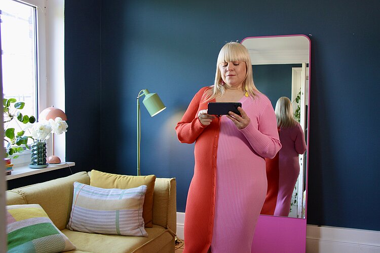 Meldodie Michelberger steht in engem Kleid vor dem Spiegel 