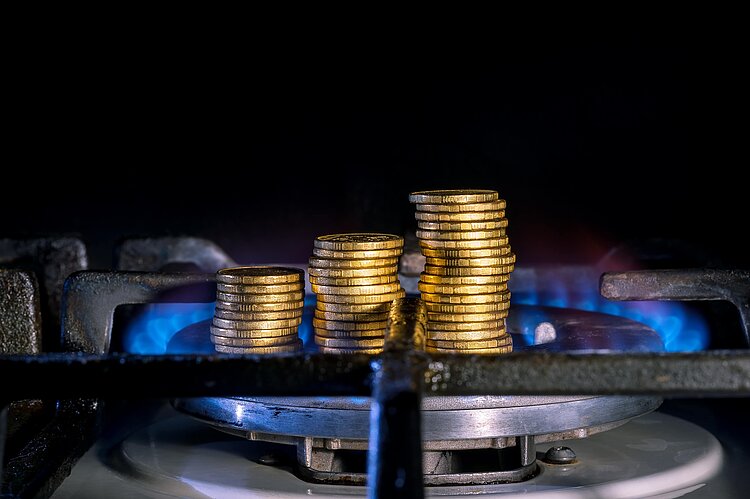 Symbolbild: Gestapelte Münzen in einer Gasherd-Flamme